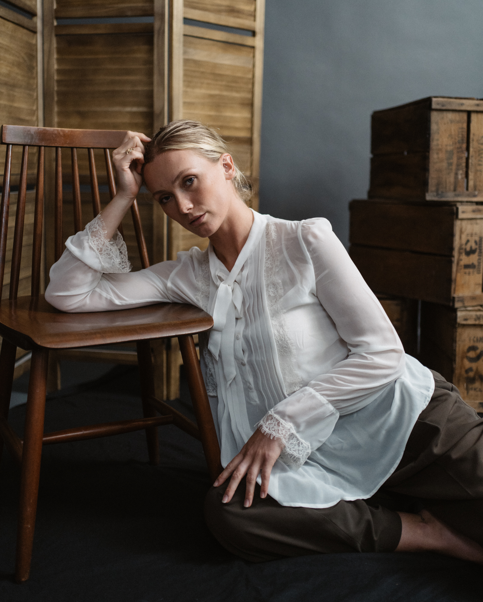 Relaxed environmental portrait beside a wooden chair